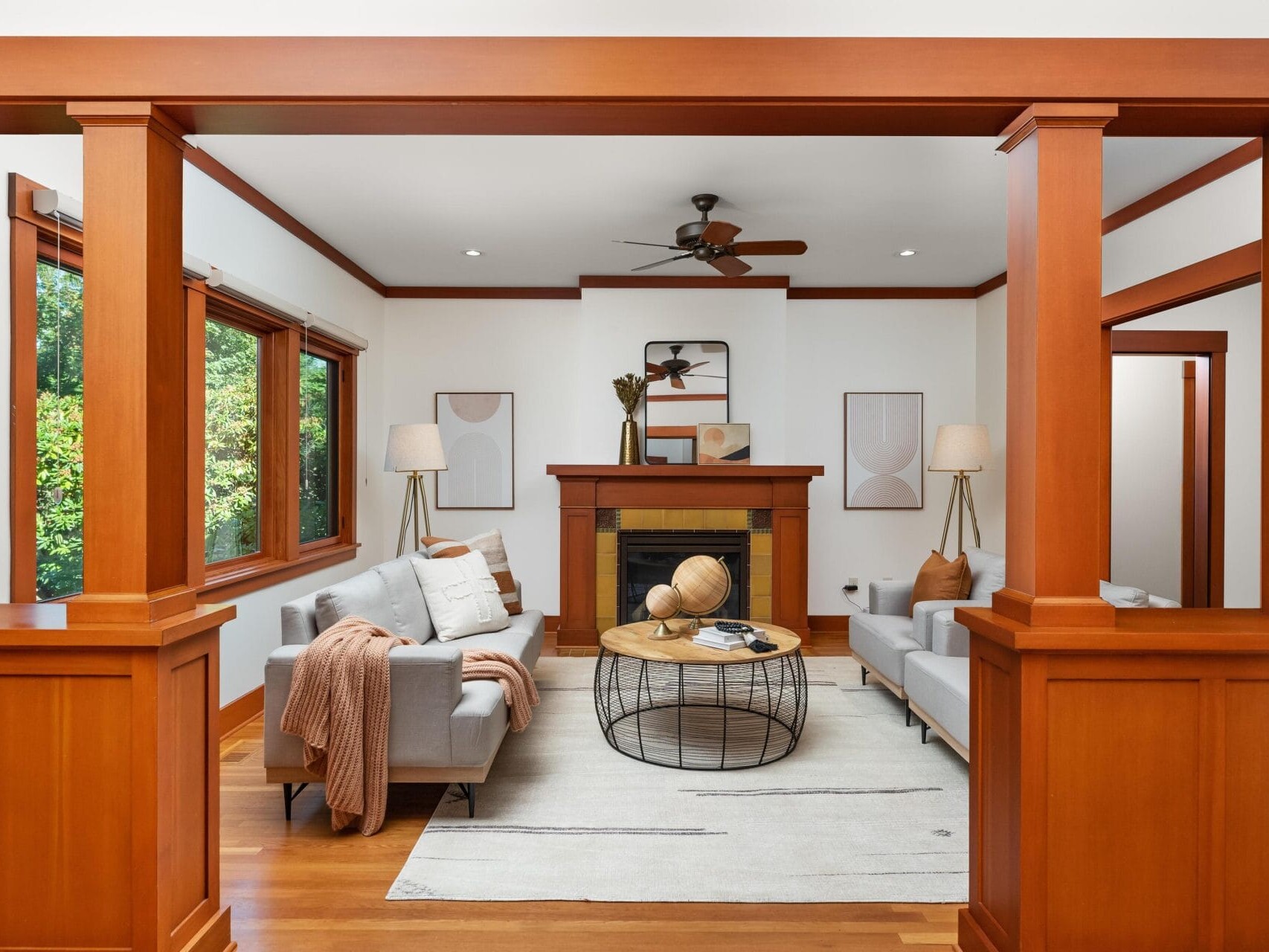 A cozy living room in Portland, Oregon, features a blend of modern and rustic decor, with light gray sofas, a wooden coffee table, and a fireplace. Warm wood accents frame the space, complemented by large windows allowing natural light in. Neutral tones create a calming ambiance.