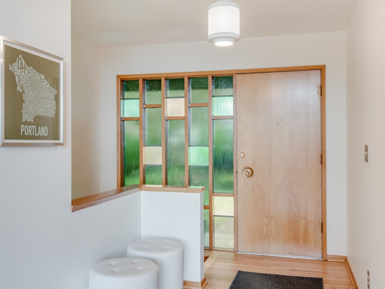 A hallway showcases a wooden door with colorful glass paneling, a modern ceiling light, and framed artwork proudly displaying 