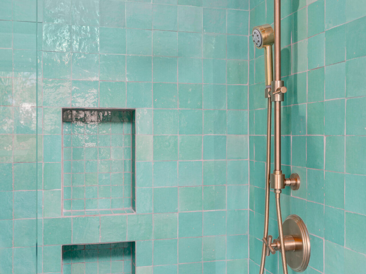In Portland, Oregon, this shower area boasts glossy turquoise tiles and a bronze-colored fixture. It features two built-in shelves and a round rain-style showerhead.