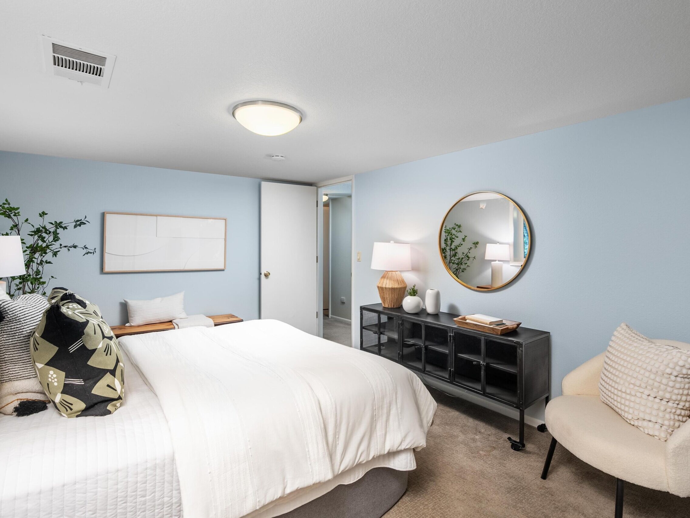 A bedroom with a mirror and a bed.